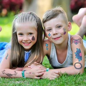 Kids smiling with colorful Halloween cartoon temporary tattoos on arms and faces outdoors