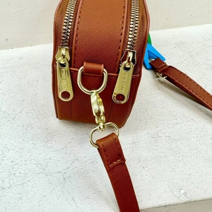 Macro detail of golden metal zippers and D-rings with engraving on brown shoulder bag