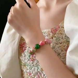 Detail of pink floral ceramic beads and gold spacers on a beaded bracelet for women