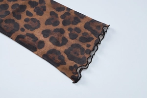 Detail of sheer mesh leopard print top showing ruffle cuffs and delicate lettuce hem edge