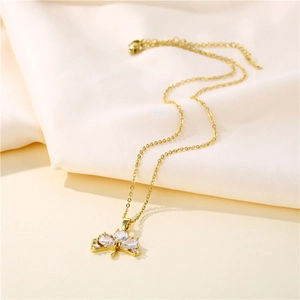 Golden stainless steel ginkgo leaf necklace with zircon stones on beige fabric