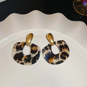 Close-up of leopard print resin earrings with golden accents on a white display tray