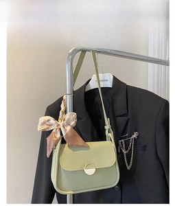 Detail of green PU leather shoulder bag with floral silk scarf and gold circular metal buckle