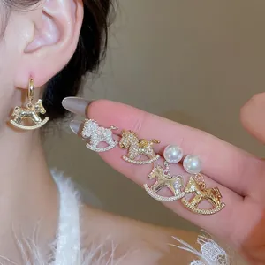 Elegant gold and silver rocking horse earrings set with pearls and zircons on a model