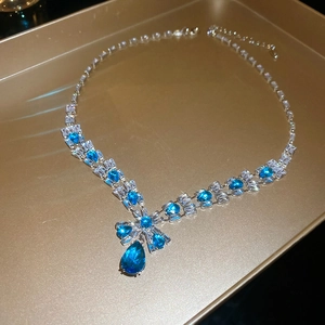 Close-up of blue and white zircon teardrop pendant on silver necklace in a gold tray