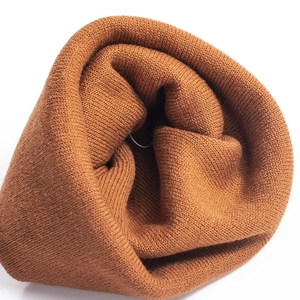 Close-up detail of caramel knitted beanie showing soft ribbed texture and warm winter fabric