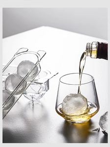 Close-up of clear round and diamond ice molds with whiskey glass and large ice balls