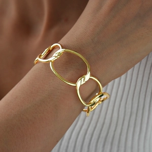 Close-up of chunky gold chain bracelet with polished oval links on a female wrist