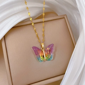 Macro shot of gold butterfly pendant with gradient resin and sparkling crystal details
