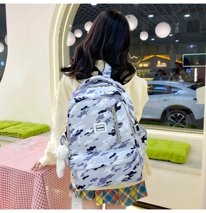 Detail view of a durable camo backpack with front zip pocket and plush charm accessory