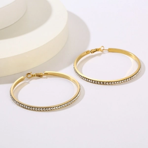Boucles d'oreilles créoles dorées en acier inoxydable avec strass sur socle blanc