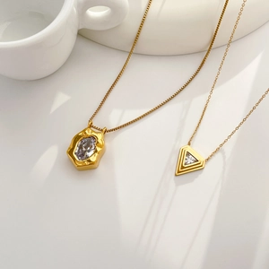 Detail of irregular and triangular gold necklaces with zircon on white ceramic