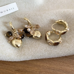 Detail of vintage gold earrings with tiger eye stone hearts and pearls on velvet