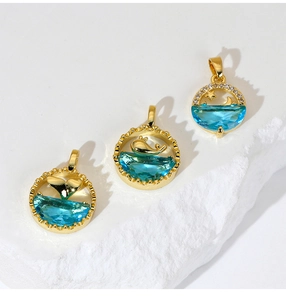 Detailed close-up of three gold dolphin and sea-themed pendants with blue faceted gems
