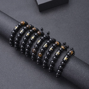 Detail of adjustable tiger eye and obsidian bead bracelets with golden alphabet charms