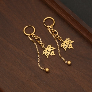 Elegant maple leaf gold drop earrings with minimalist twisted chain on dark wood tray