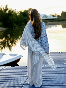 Vue extérieure d'un pull à motif de voilier avec pantalon rayé au bord d'un lac au coucher du soleil