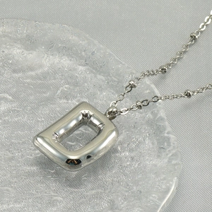 Polished silver stainless steel 18K bubble letter D pendant necklace on glass