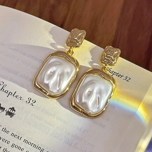 Detailed macro of vintage pearl earring with hammered gold texture on an open book
