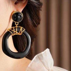 Gros plan de boucles d'oreilles géométriques en résine noire et métal doré