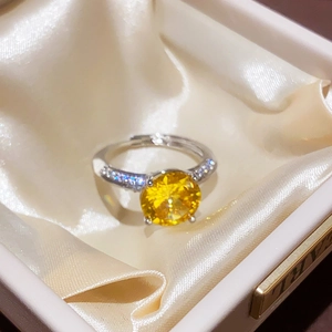 Detailed macro view of an adjustable silver ring with a sparkling oval yellow gemstone