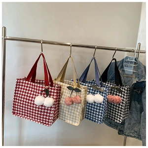 Detail view of four houndstooth tote bags in red, beige, blue and black with cherry charms