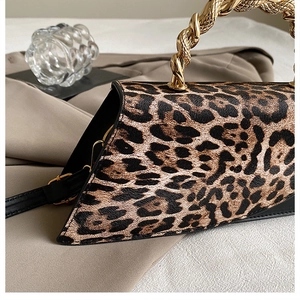 Detail of leopard print crossbody bag with golden spiral handle and textured PU leather