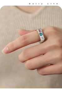 Detail shot of a silver band ring with three colorful gemstones worn on the hand