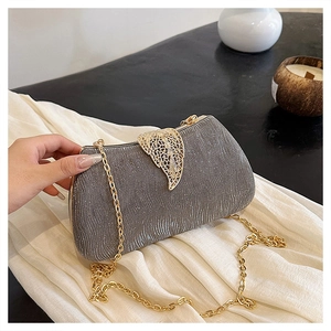 Macro shot of silver glitter box clutch with elegant golden leaf-shaped metal clasp