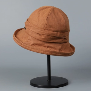 Detailed side view of a brown linen bucket hat on a professional black metal stand.