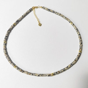 Macro detail of natural dalmatian jasper stone necklace with 925 silver heart tag