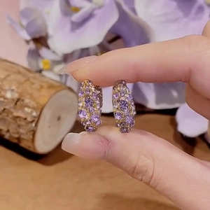 Detailed close-up of chunky gold hoops featuring full purple cubic zirconia inlay