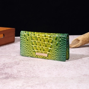 Detail of green-yellow gradient crocodile pattern wallet with polished metal fastener