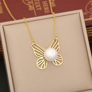 Macro detail of golden butterfly necklace with white pearl on a beige jewelry box