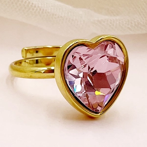 Détail d'une bague dorée ajustable ornée d'une pierre précieuse rose en forme de cœur