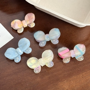 Set of five elegant butterfly hair clips in pastel colors on a rustic wooden table