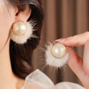 Detailed close-up of an elegant pearl earring with fluffy white fur trim and gold edge