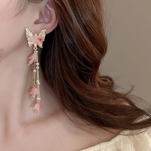 Gros plan de boucles d'oreilles papillon dorées à pampilles roses sur un mannequin