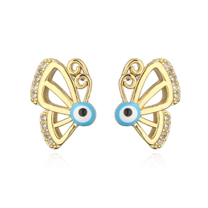Macro detail of 18K gold butterfly stud earrings featuring zircon and evil eye motifs