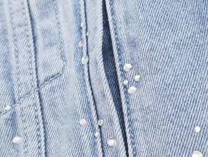 Gros plan de strass étincelants sur une veste en jean bleu clair avec coutures précises