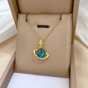 Detail of gold planet necklace with blue nebula sphere and sparkling crystal orbital ring