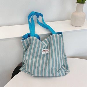Dettaglio della borsa tote a righe bianche e blu che mostra la trama della tela e i manici