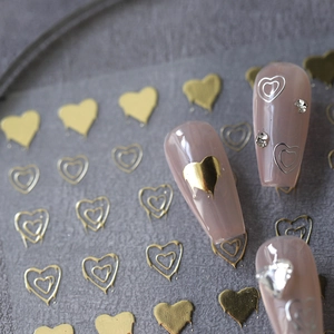 Golden heart nail art stickers with fluid metallic texture on pink manicured nails