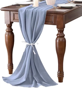 Blue chiffon table runner gathered with a white ribbon on a wooden table setting