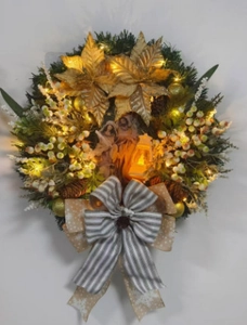 Detail of Christmas wreath with warm LED lights, gold poinsettia and nativity scene decor