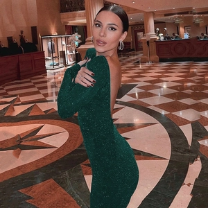 Detailed backless design of this green glitter cocktail dress on a model in a luxury hall