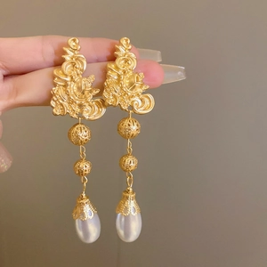 Detailed close-up of vintage gold floral earrings with delicate drop pearls
