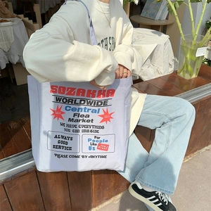 Close-up of a blue canvas tote bag featuring vintage American graphic prints and lettering