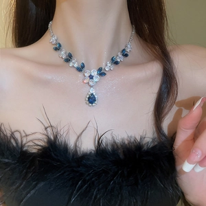 Close-up of blue teardrop crystal pendant necklace on model's neck with zircon accents