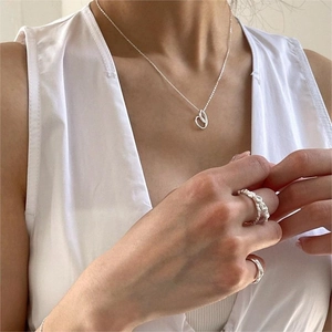 Detail of 925 sterling silver heart necklace and textured minimalist ring on model